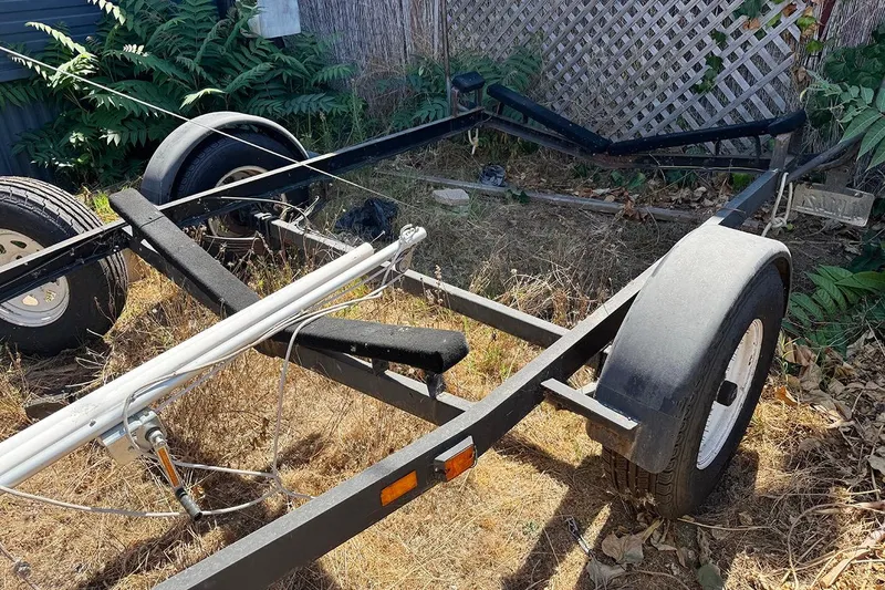 Slide: The Image of Trailer for 2005 MacGregor 26M Powersailer in overgrown yard. - 36