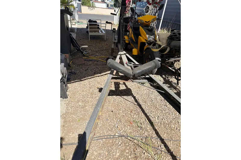 Slide: The Image of Trailer for 2005 MacGregor 26M Powersailer on gravel driveway with yellow vehicle nearby. - 37