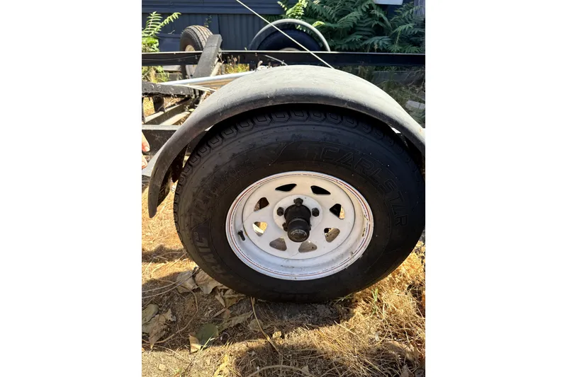 Slide: The Image of Trailer wheel of a 2005 MacGregor 26M Powersailer on dry grass. - 38
