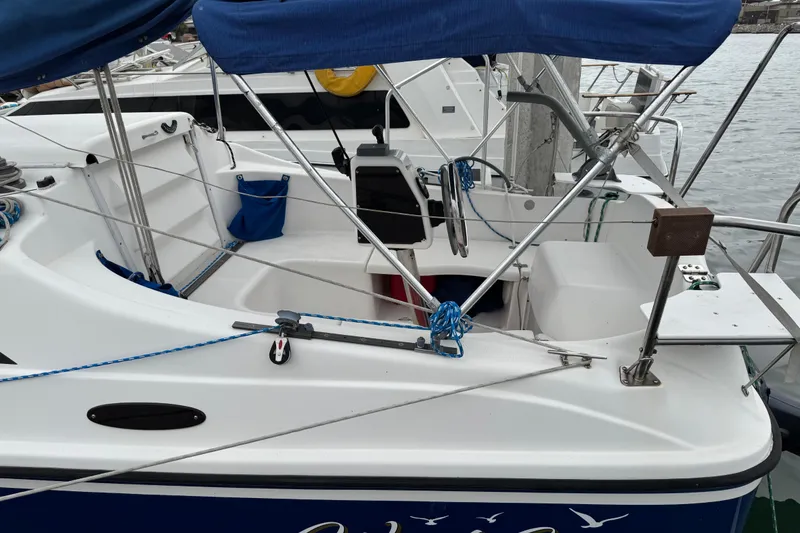 Slide: The Image of 2005 MacGregor 26M Powersailer docked, featuring blue canopy and white deck. - 4