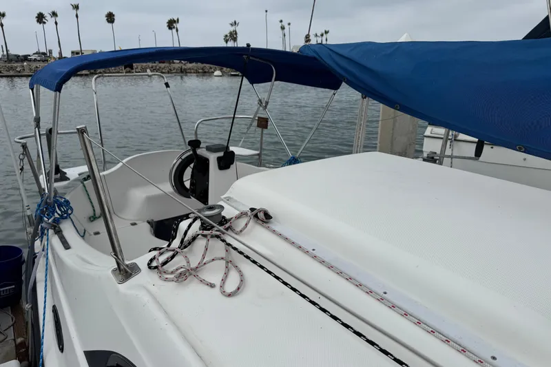 Slide: The Image of 2005 MacGregor 26M Powersailer with blue canopy docked at marina. - 6