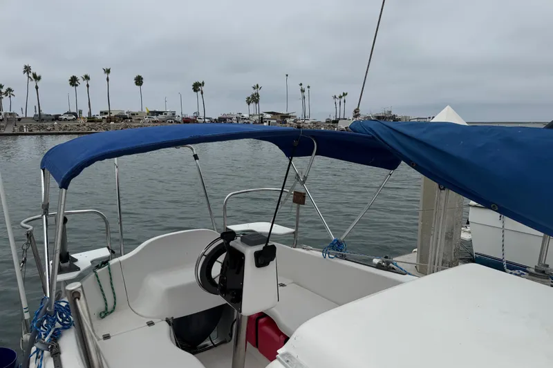Slide: The Image of 2005 MacGregor 26M Powersailer docked, featuring blue canopy and steering wheel, with palm trees in background. - 7