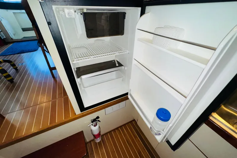 Slide: The Image of 2004 Camano 31 Troll boat interior with open refrigerator and wooden flooring. - 10