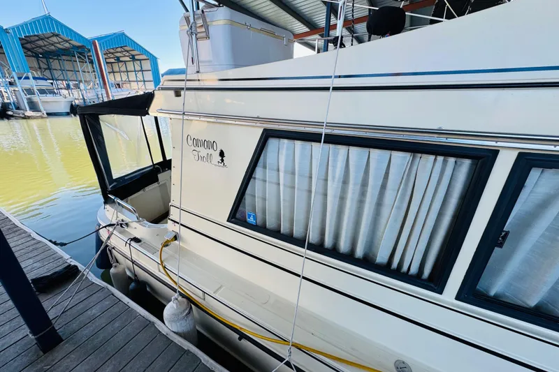 Slide: The Image of 2004 Camano 31 Troll boat docked at marina with blue boathouses. - 20