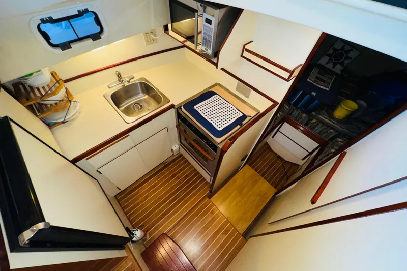 Slide: The Image of 2004 Camano 31 Troll boat interior kitchen with sink, stove, and wooden flooring. - 8