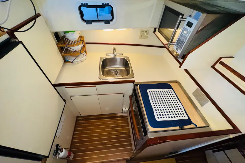 Slide: The Image of Compact kitchen area in a 2004 Camano 31 Troll boat, featuring a sink and microwave. - 9