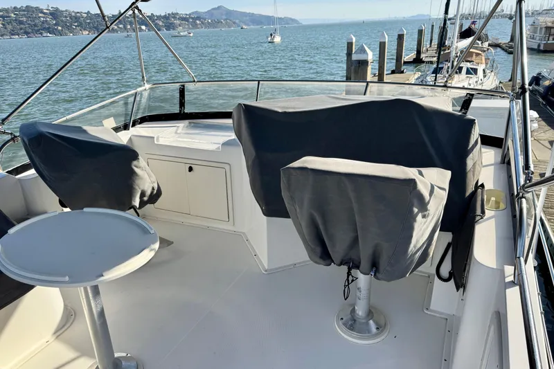 Slide: The Image of 2001 Sabre Sedan Bridge boat deck with covered seats, table, and scenic waterfront view. - 22