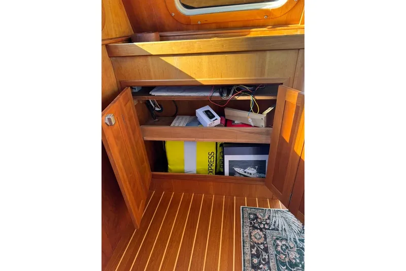 Slide: The Image of Open wooden cabinet on 2001 Sabre Sedan Bridge boat, revealing storage items and wiring. - 26