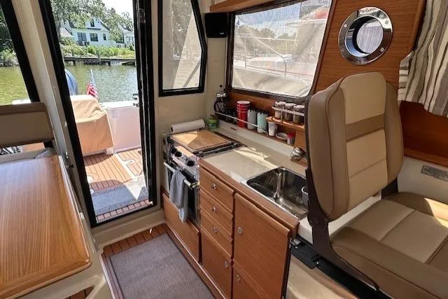 Slide: The Image of 2024 Ranger Tugs R-27 interior with kitchenette, seating, and outdoor view. - 10