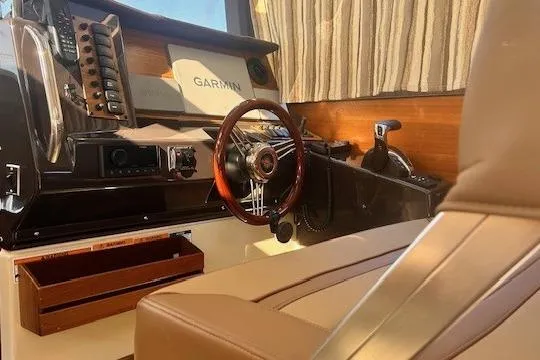 Slide: The Image of 2024 Ranger Tugs R-27 interior helm with Garmin navigation system and wooden steering wheel. - 16