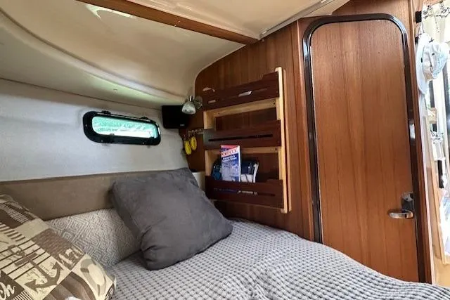 Slide: The Image of 2024 Ranger Tugs R-27 cabin interior with cozy bed and wooden storage shelves. - 18