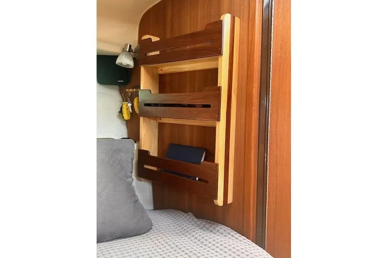 Slide: The Image of 2024 Ranger Tugs R-27 interior with wooden shelves and cozy bedding. - 20