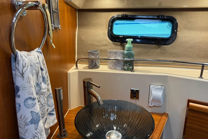 Slide: The Image of 2024 Ranger Tugs R-27 bathroom with modern sink, toilet, and nautical decor. - 25