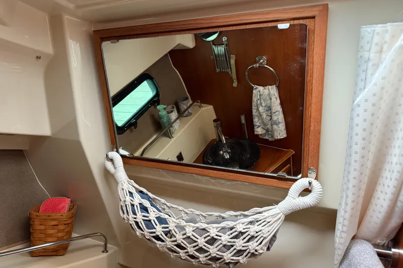 Slide: The Image of 2024 Ranger Tugs R-27 bathroom with glass sink, towel, and porthole window. - 26