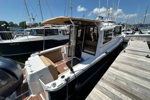 Slide: The Image of 2024 Ranger Tugs R-27 boat docked at marina, featuring spacious deck and modern design. - 3