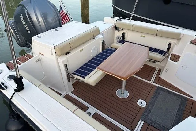 Slide: The Image of 2024 Ranger Tugs R-27 boat interior with seating, table, and Yamaha engine. - 4