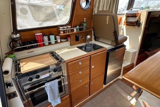 Slide: The Image of 2024 Ranger Tugs R-27 interior kitchen with stove, sink, and compact fridge. - 6
