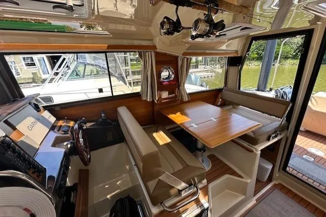 Slide: The Image of 2024 Ranger Tugs R-27 interior with helm, dining area, and large windows. - 8