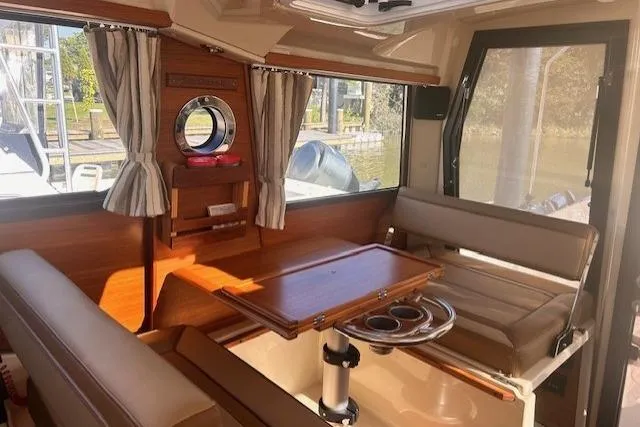 Slide: The Image of 2024 Ranger Tugs R-27 interior with seating, table, and windows. - 9