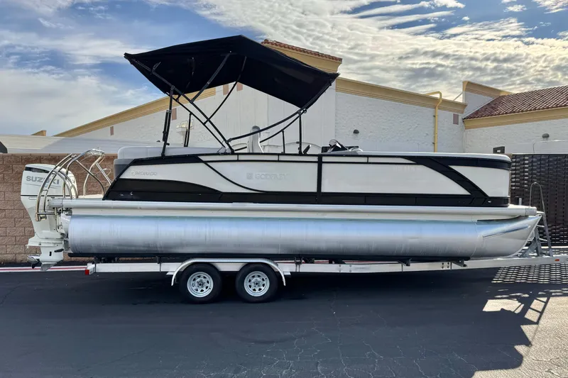 The Image of 2020 Godfrey Monacco 255 SD pontoon boat on trailer, parked outdoors under a blue sky. - 0