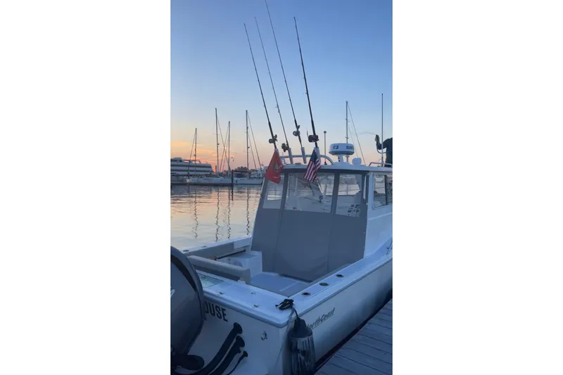 Slide: The Image of 2023 NorthCoast 255HT boat docked at sunset with fishing rods and flags. - 6