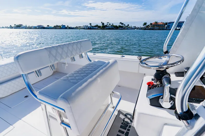 Slide: The Image of 2025 Contender 32 ST boat interior with steering wheel and seating, overlooking calm waters. - 27