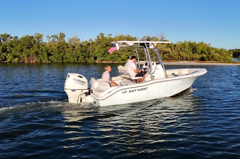 Slide: The Image of 2020 Key West 219 FS boat cruising on water with passengers, Suzuki engine visible. - 21