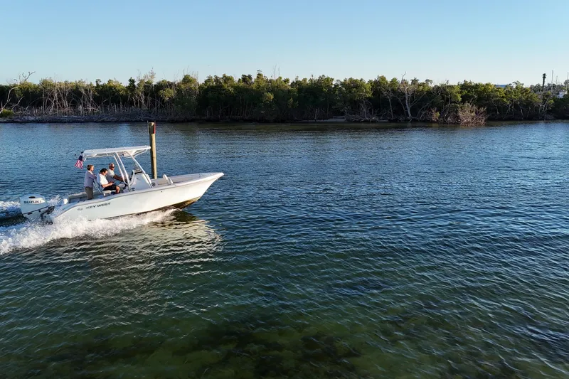 Slide: The Image of 2020 Key West 219 FS boat cruising on calm water near a forested shoreline. - 22