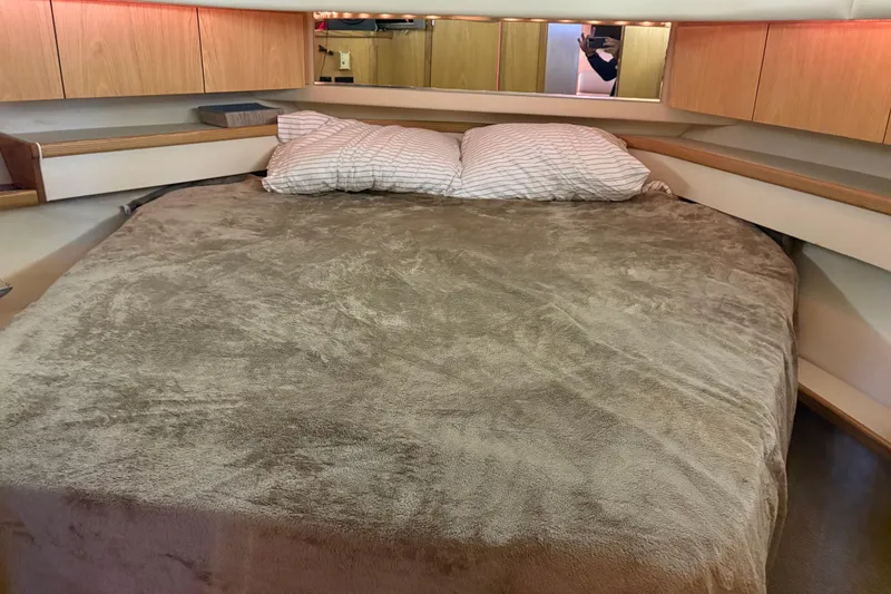 Slide: The Image of Cozy bedroom interior of 1999 Tiara Yachts 4000 Express with plush bedding and wooden cabinets. - 14