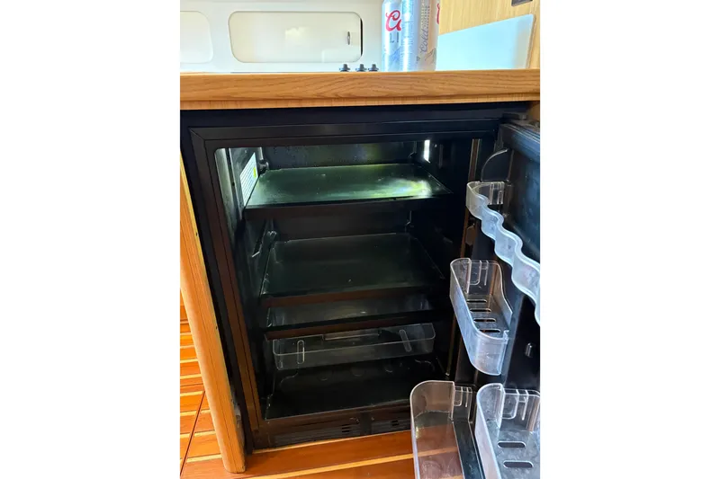 Slide: The Image of Refrigerator inside 1999 Tiara Yachts 4000 Express, featuring wooden cabinetry and empty shelves. - 43