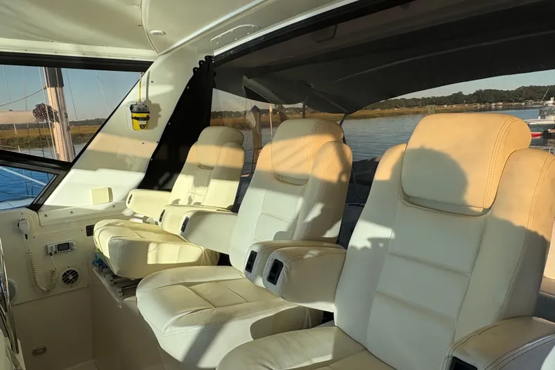 Slide: The Image of 1999 Tiara Yachts 4000 Express interior with white seating and canopy, docked by calm waters. - 5