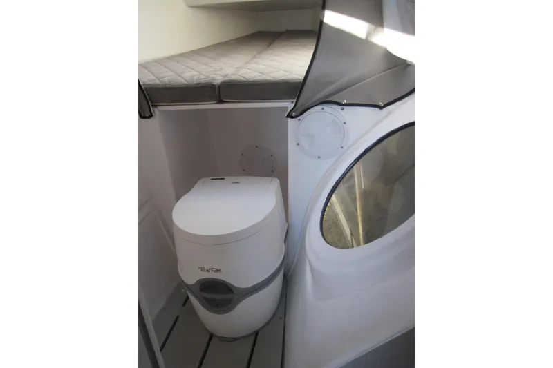 Slide: The Image of Interior of 2022 Corsair 880 Standard boat with compact toilet and cushioned sleeping area. - 24