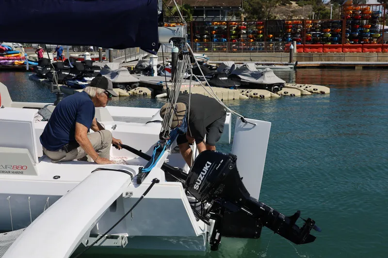 Slide: The Image of Two people working on a 2022 Corsair 880 Standard sailboat at a marina. - 28
