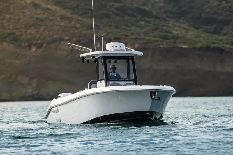 Slide: The Image of 2025 Everglades 285 Center Console boat cruising on water near rocky shoreline. - 24