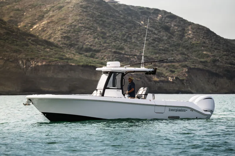 Slide: The Image of 2025 Everglades 285 Center Console boat cruising near rocky coastline. - 3