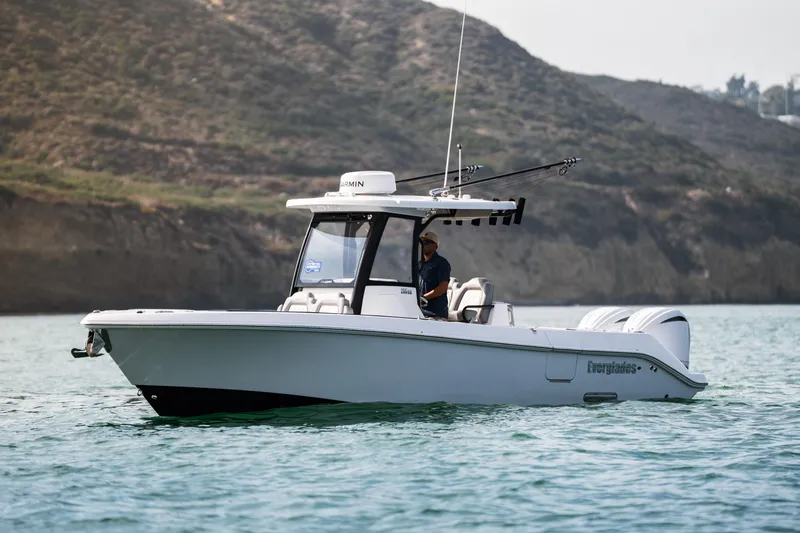 Slide: The Image of 2025 Everglades 285 Center Console boat on water, with scenic rocky background. - 4