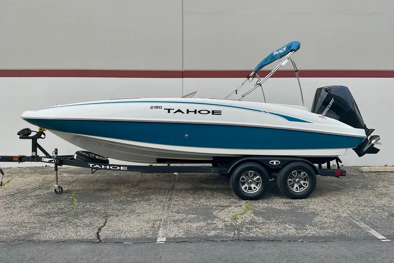 Slide: The Image of 2026 Tahoe 2150 boat on trailer, blue and white design, parked outdoors. - 2