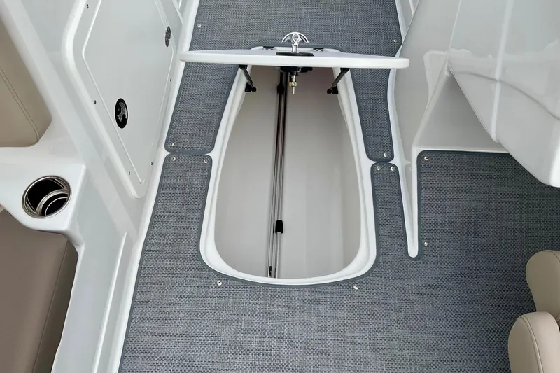 Slide: The Image of 2026 Tahoe 2150 boat interior storage compartment with gray carpet and cup holder. - 24