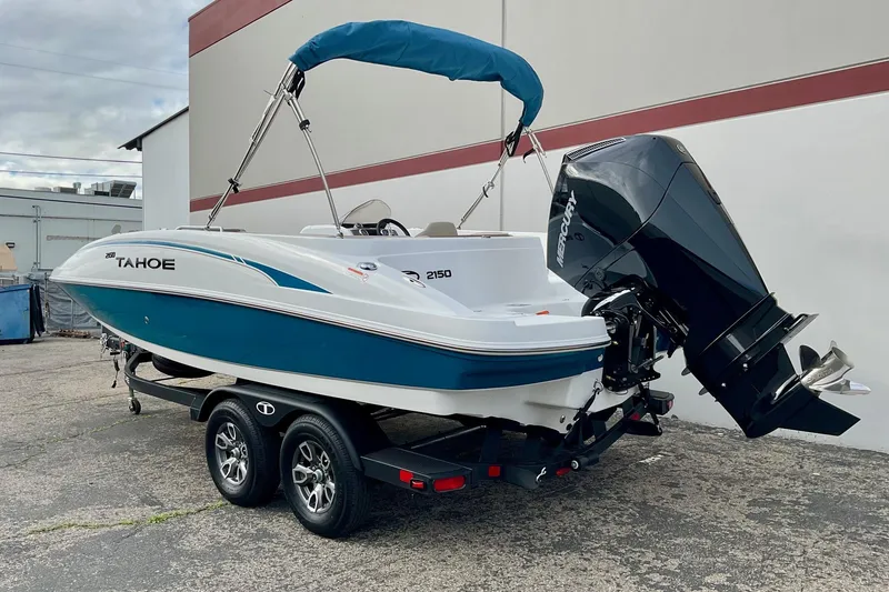 Slide: The Image of 2026 Tahoe 2150 boat with outboard motor on a trailer, parked outdoors. - 3