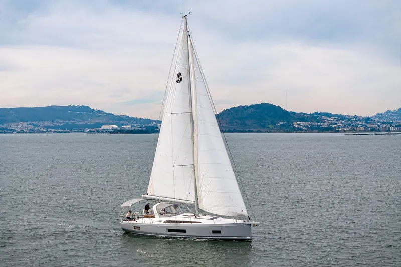 Slide: The Image of 2020 Beneteau Oceanis 46.1 sailing on calm waters with scenic hills in the background. - 58