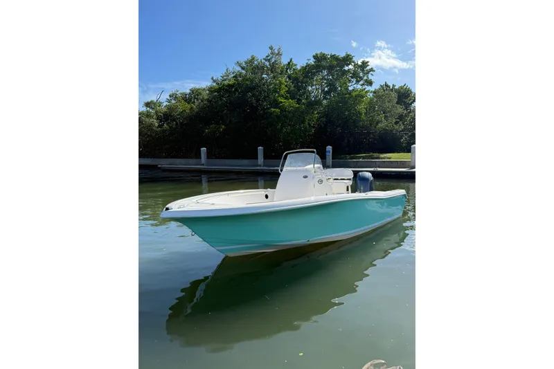 Slide: The Image of 2020 Tidewater 198 CC Adventure boat docked on calm water, sunny day. - 2