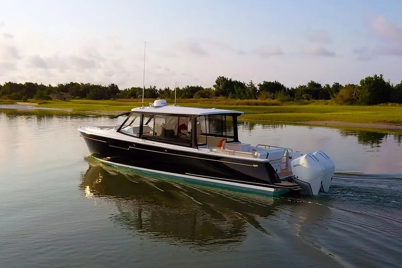 Slide: The Image of 2026 MJM 3 boat cruising on calm water near a grassy shoreline. - 10