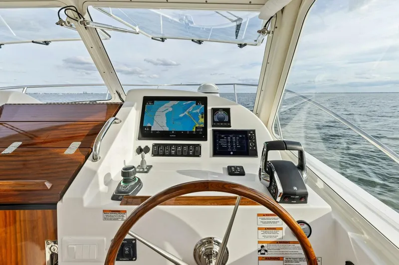 Slide: The Image of 2025 MJM 35 yacht helm with navigation screens and wooden steering wheel on open water. - 15