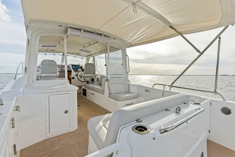 Slide: The Image of 2025 MJM 35 boat interior with seating, helm, and canopy on open water. - 24