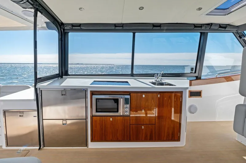 Slide: The Image of Modern kitchen on MJM 4 yacht, featuring sleek cabinetry, appliances, and ocean view. Model year 2025. - 12