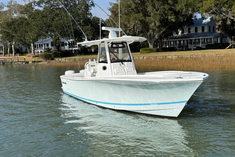 Slide: The Image of 2020 Regulator 31 boat on calm water near shoreline with trees and houses. - 1
