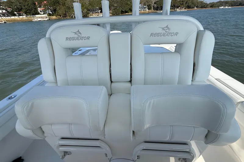 Slide: The Image of 2020 Regulator 31 boat with white cushioned seats on a calm water backdrop. - 18