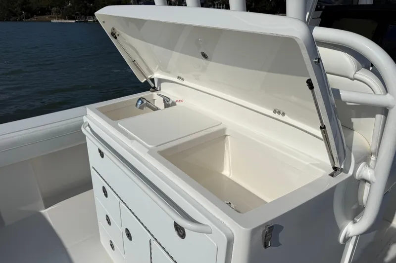 Slide: The Image of 2020 Regulator 31 boat with open storage compartment and sink, docked by the water. - 20