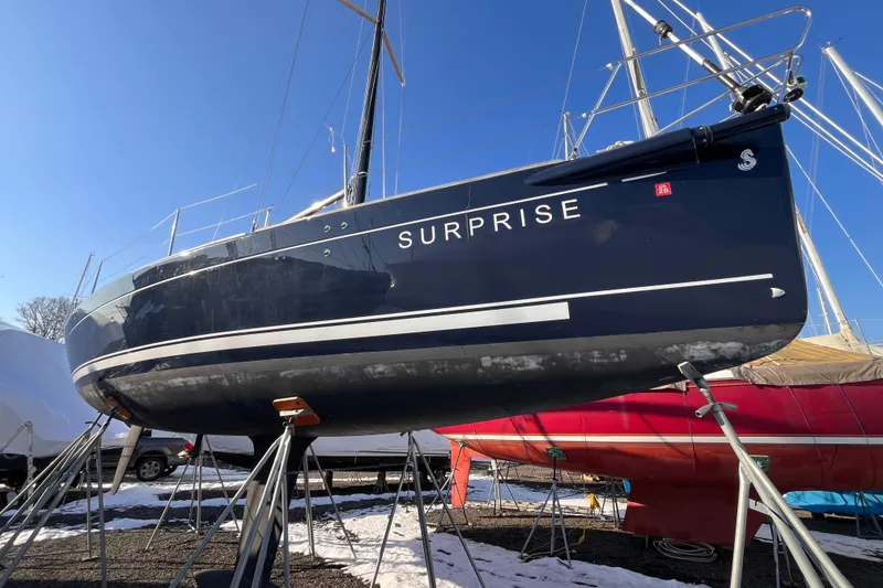 Slide: The Image of 2007 Beneteau First 10R sailboat named "Surprise" on stands, blue hull, sunny day. - 10