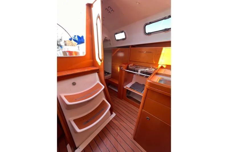 Slide: The Image of Interior of 2007 Beneteau First 10R sailboat with wooden flooring and compact kitchen area. - 52